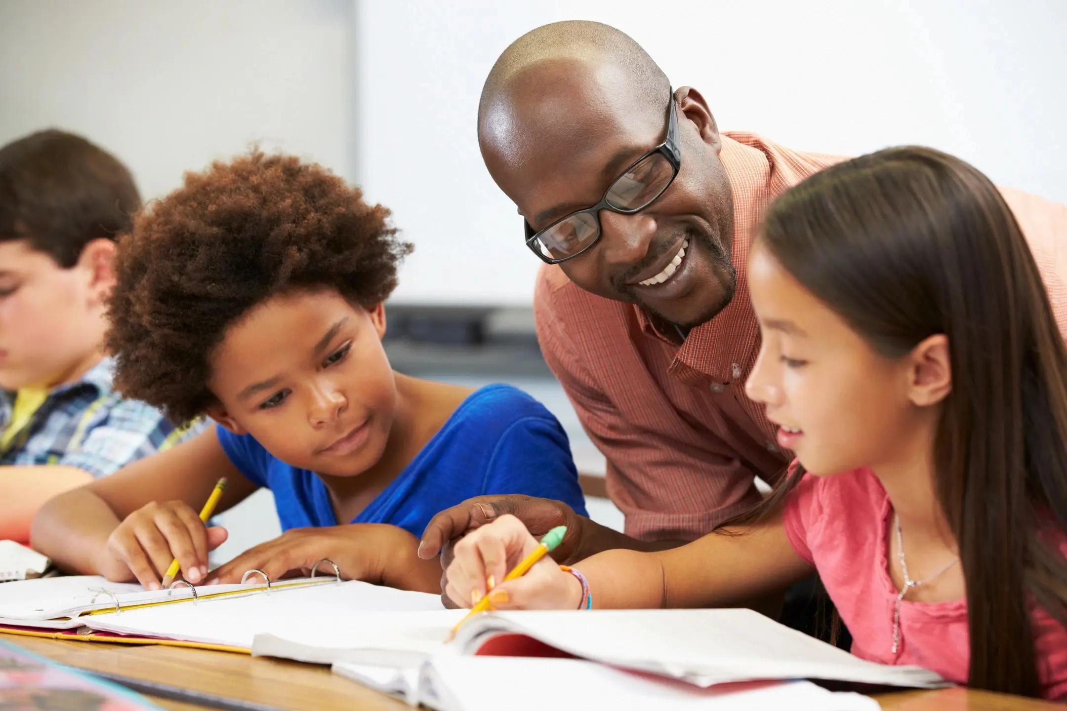 Teacher helping two children with their schoolwork.