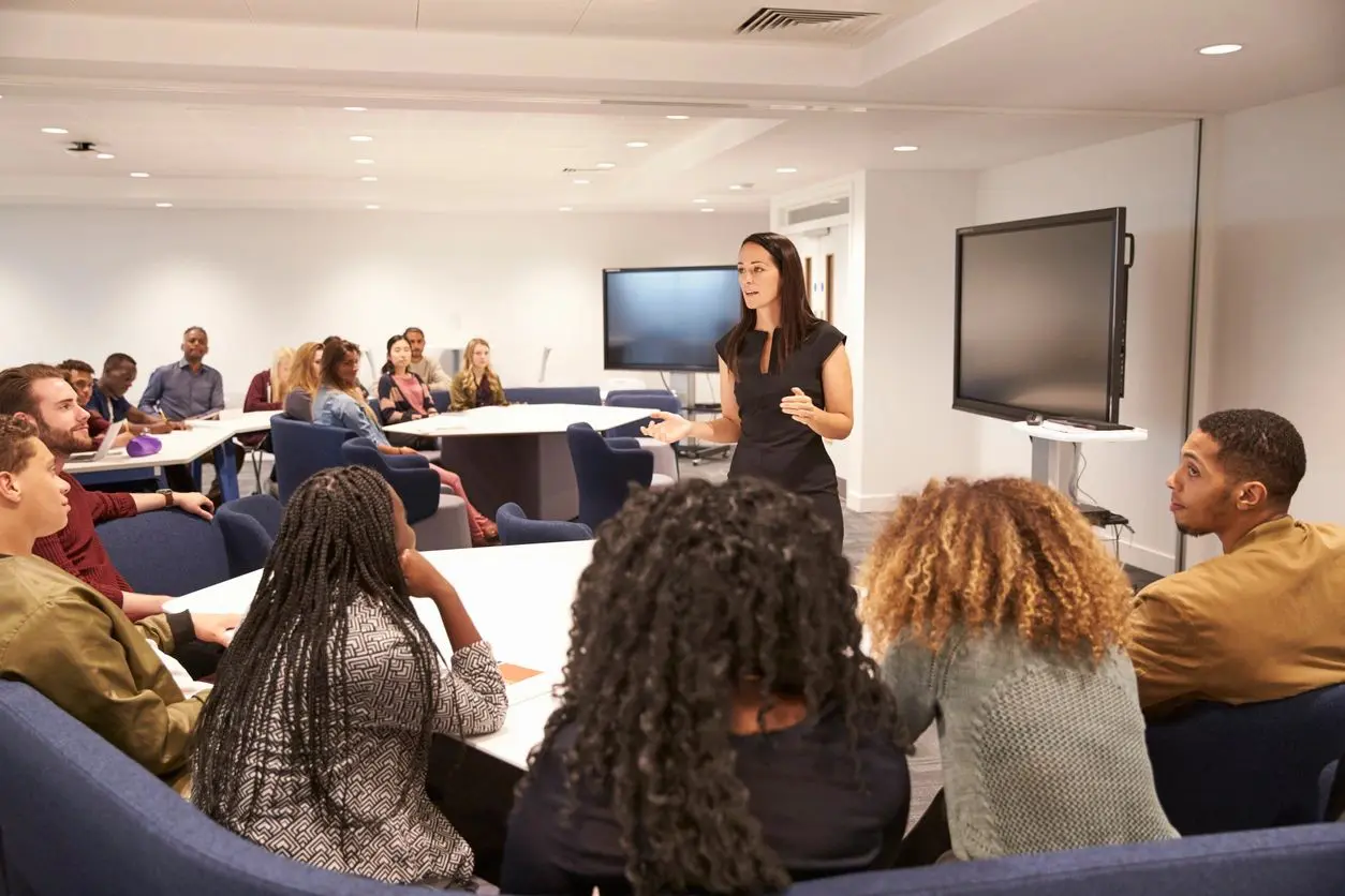 Instructor engaging with a group of students in a modern classroom.