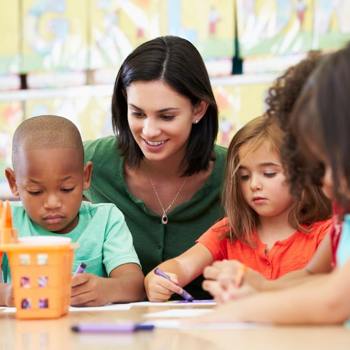 Teacher helping young children with a classroom activity.